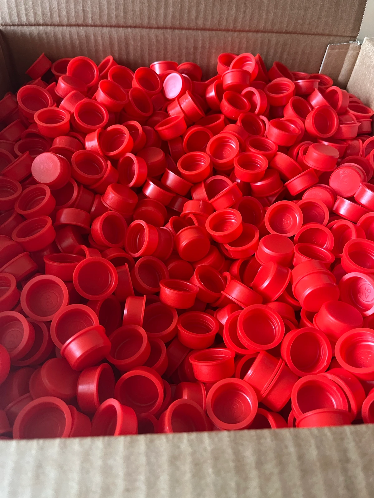 Viele rote HDPE-Stopfen mit 26 mm Durchmesser in einem Vorratskarton